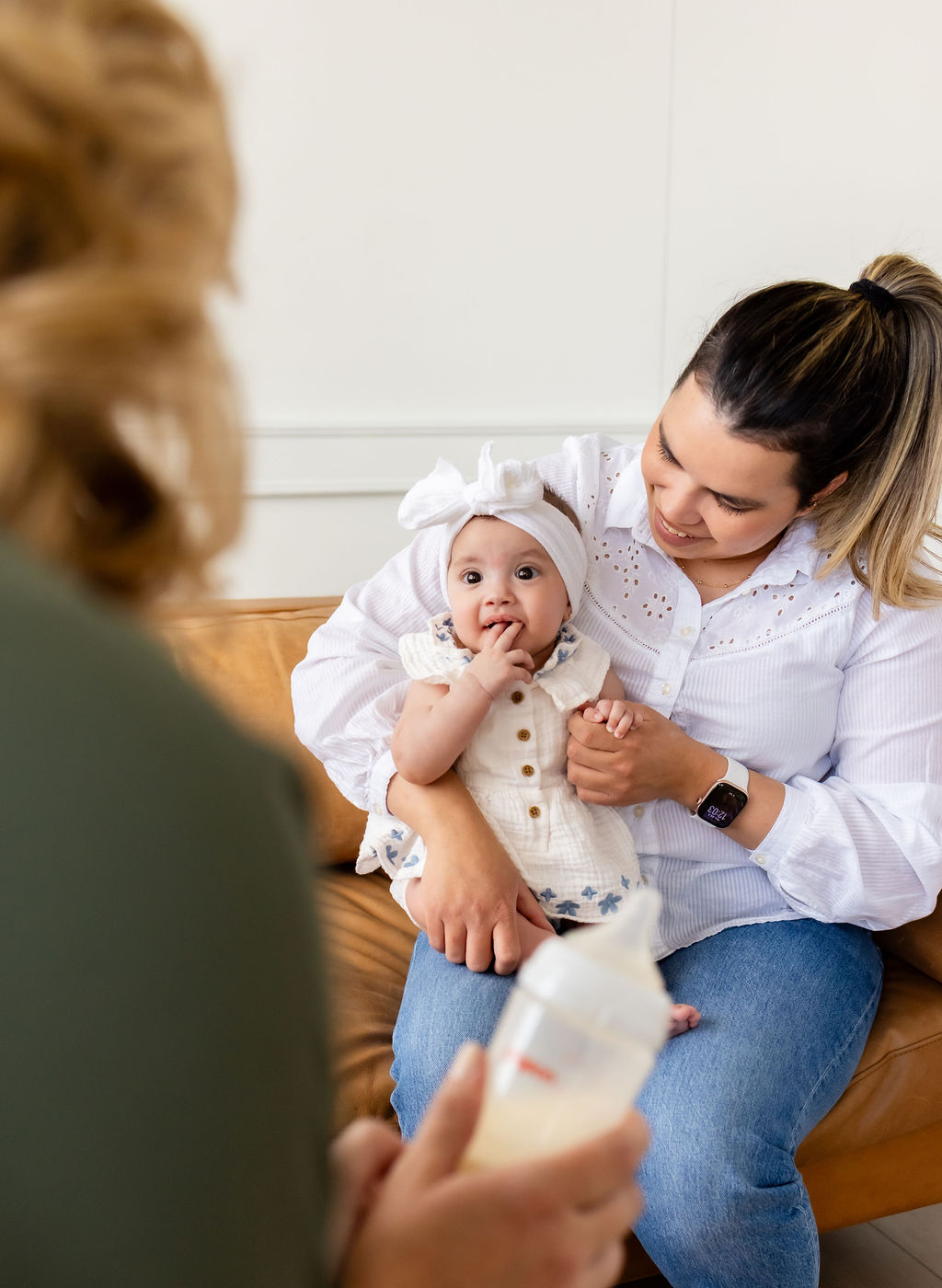 A caregiver holding an infant during a conversation with Ally Gore, who holds a bottle