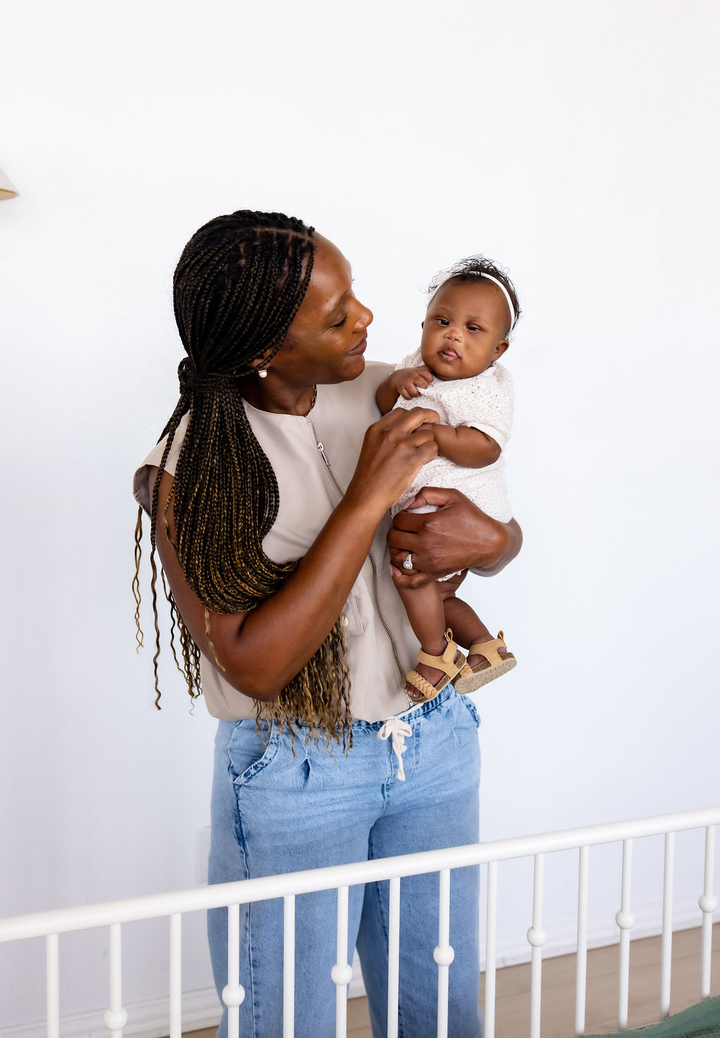 A caregiver holding her infant beside a crib