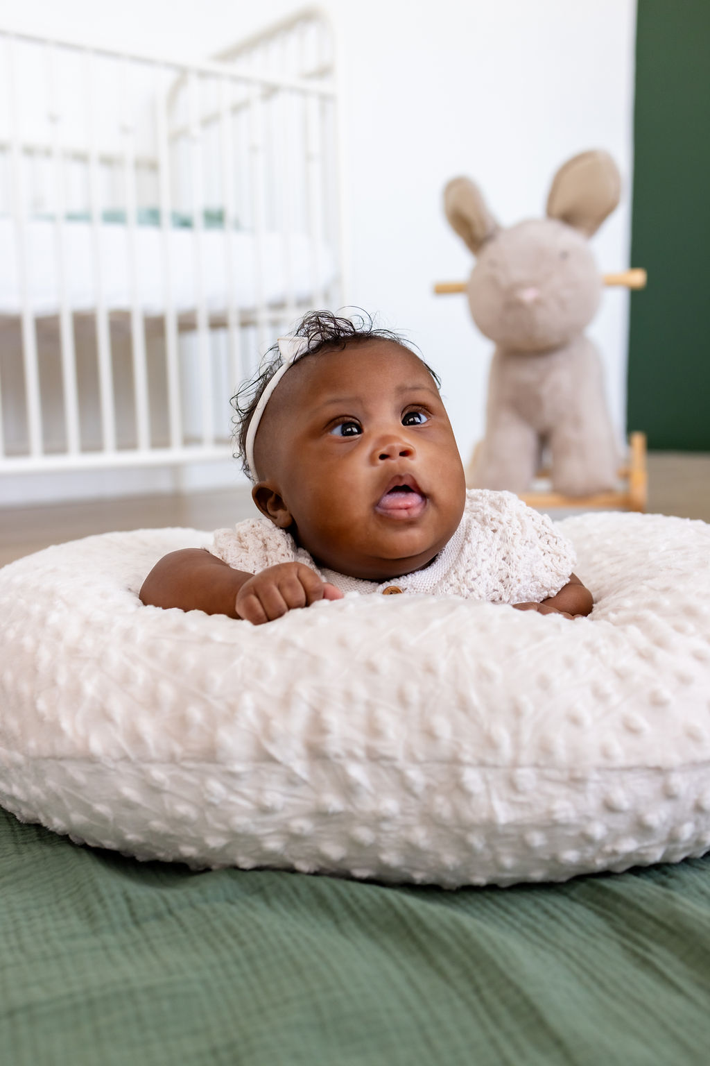 An awake infant looking up during tummy time on a white cushion
