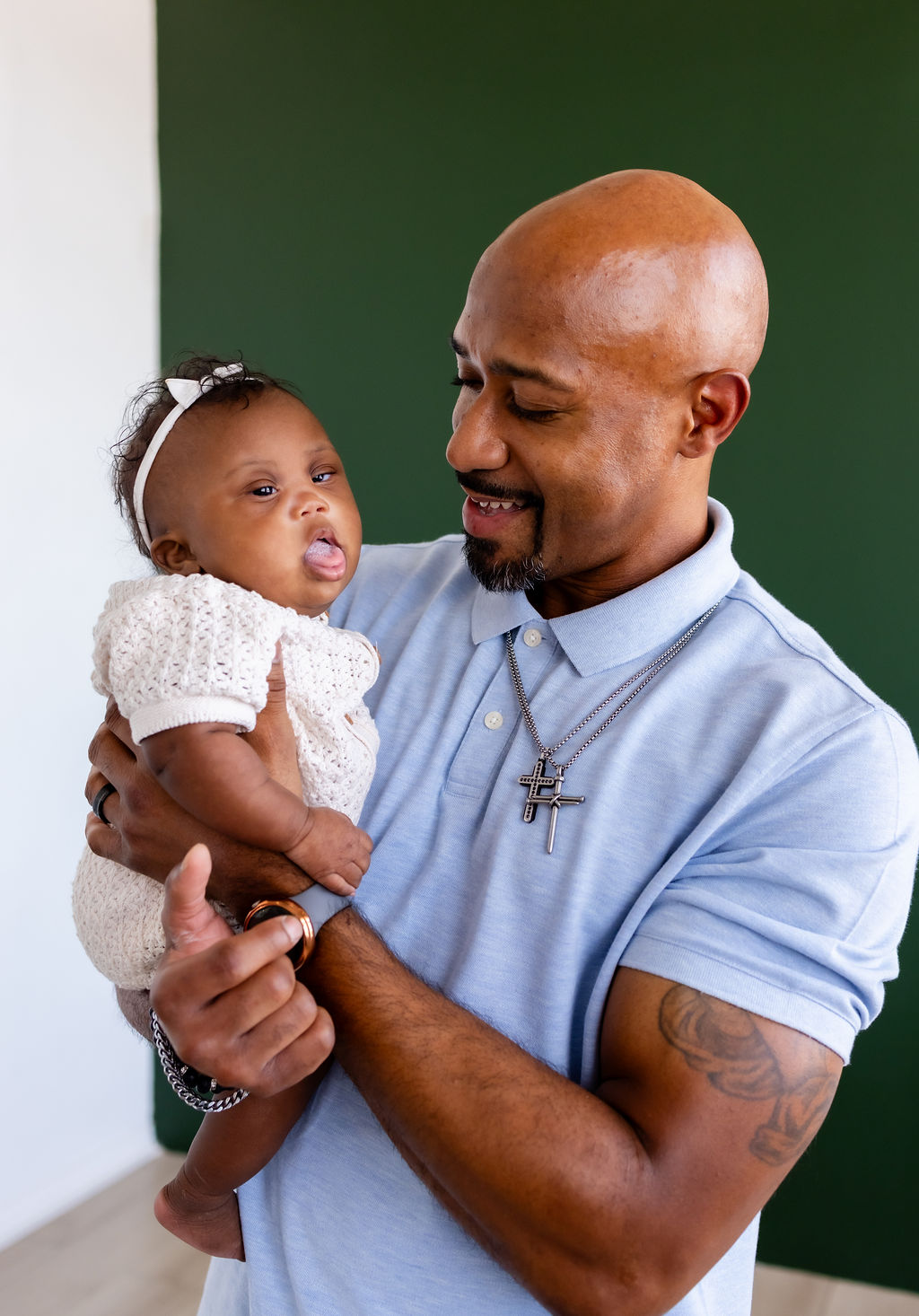 A father holding his infant upright and smiling toward the baby